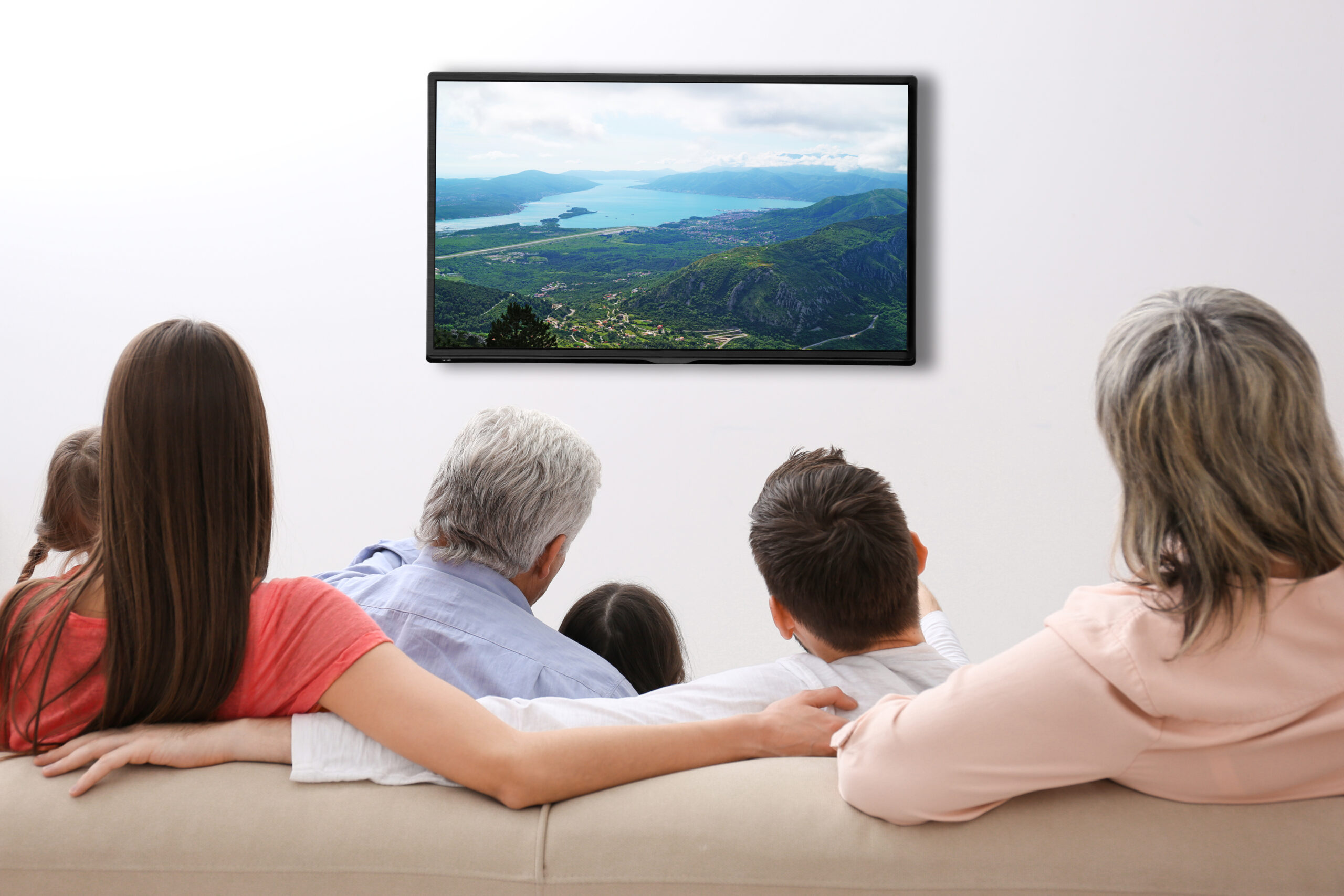 Rodzina ogląda TV siedząc na kanapie