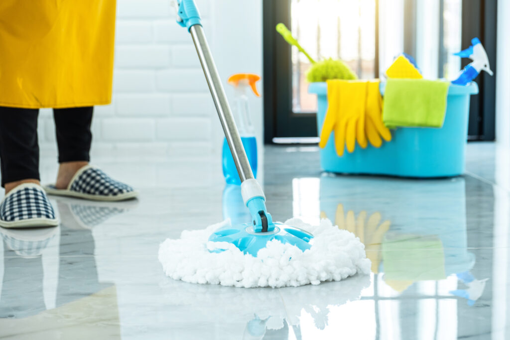 Kobieta sprząta dom mopem obrotowym orz innymi akcesoriami do sprzątania